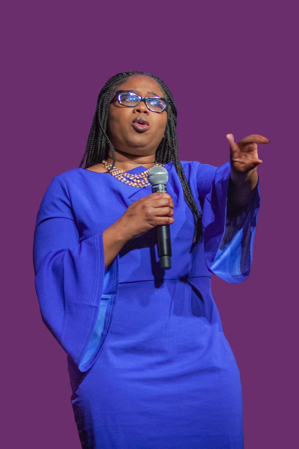 Nikesha Tilton speaking into a handheld microphone with an open gesture